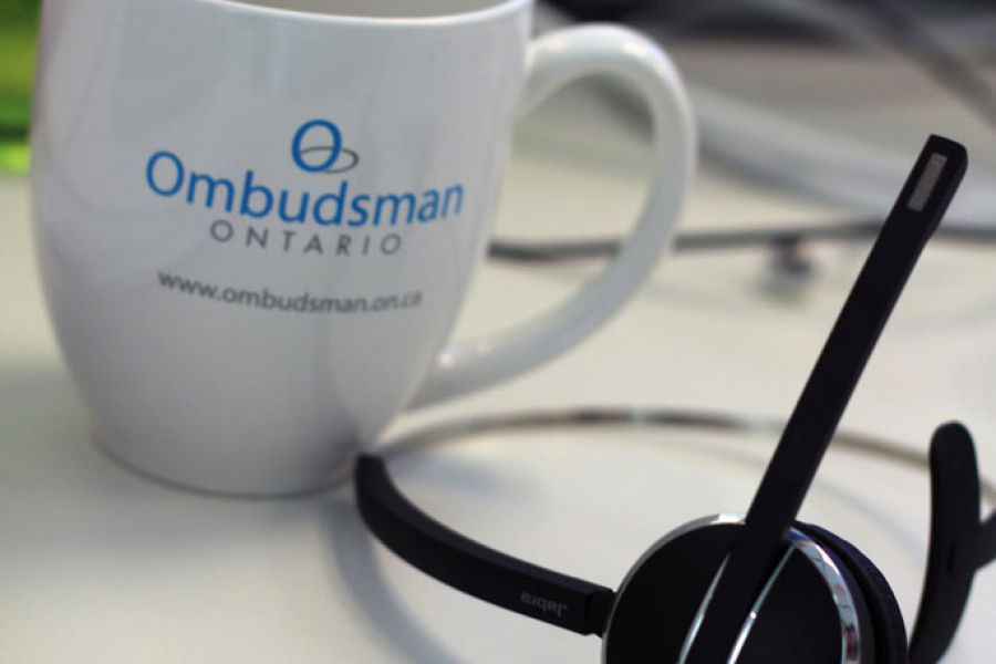 Coffee mug with Ombudsman Ontario logo, on a desk next to a headset
