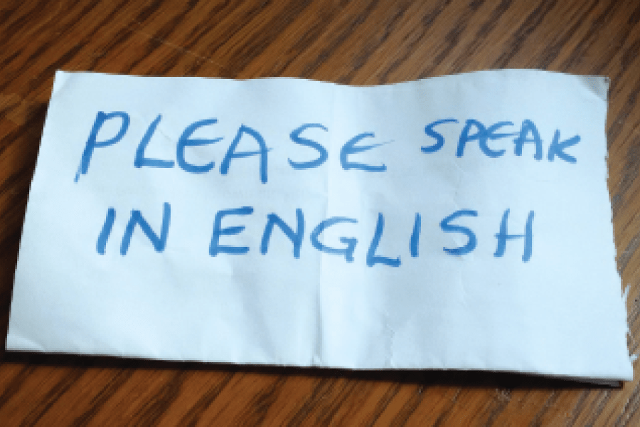 Morceau de papier avec "Please speak in English" inscrit dessus