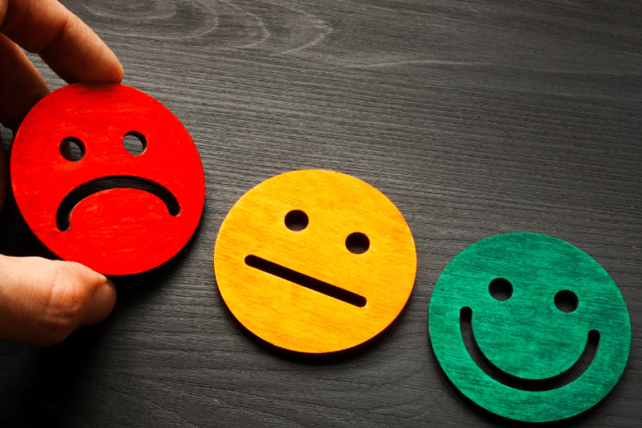 Une main disposant trois icônes de visage (visage triste rouge, visage neutre jaune, visage heureux vert) Une main disposant trois icônes de visage (visage triste rouge, visage neutre jaune, visage heureux vert)