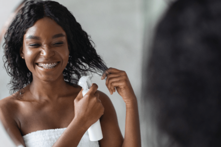 Personne pulvérisant les cheveux Une personne vaporisant ses cheveux avec une bouteille