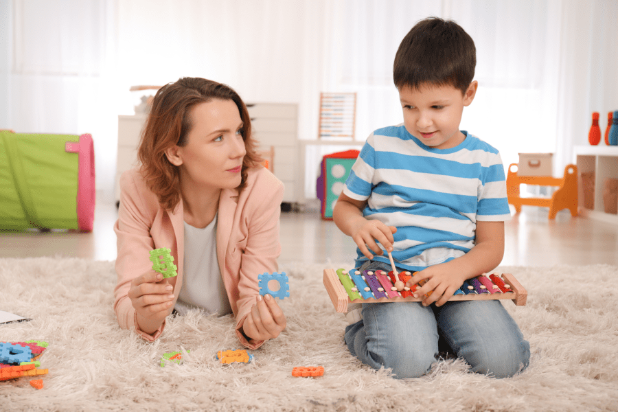 Adult and child laying on floor with toys An adult and a child on the floor playing with toys.