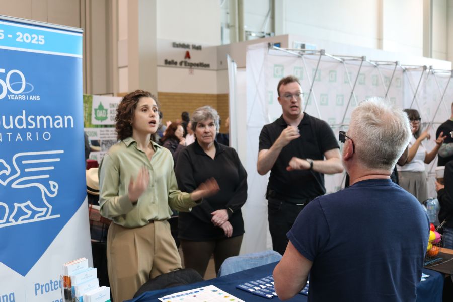  Un membre du personnel, aux côtés d'un interprète ASL, parle à une personne lors d'un événement