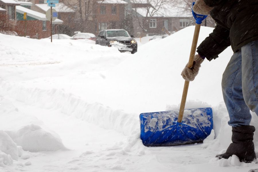 Une personne pelletant la neige dans une rue résidentielle Une personne pelletant la neige dans une rue résidentielle